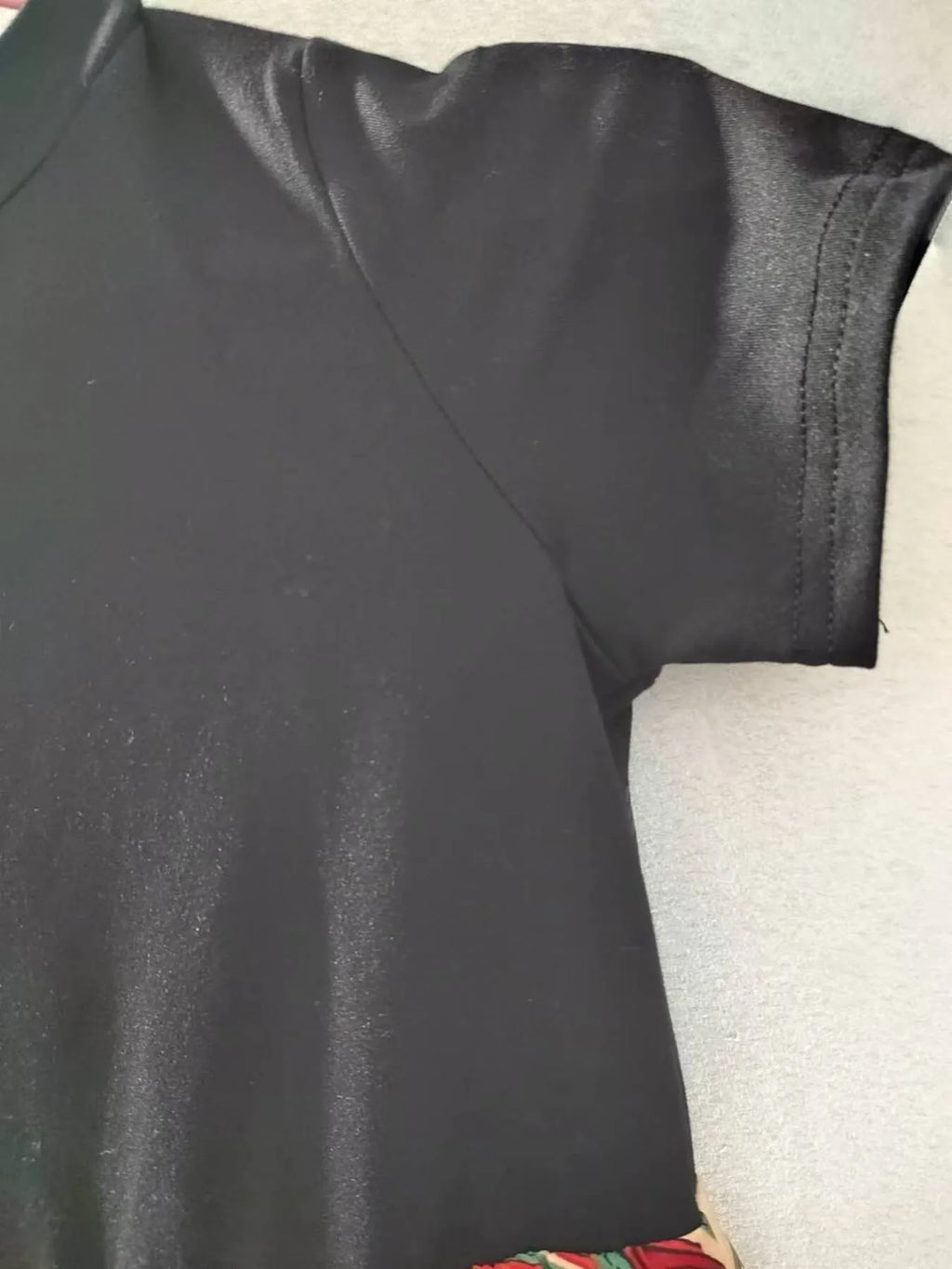 Close-up of a black short sleeve dress showing the smooth fabric and detailed sleeve design.